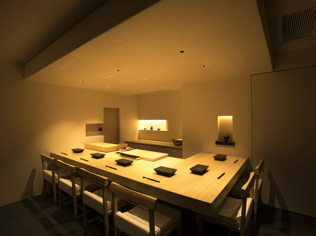 A separate six-seat wooden sushi counter room at Hakkoku, with chairs facing the central preparation surface.