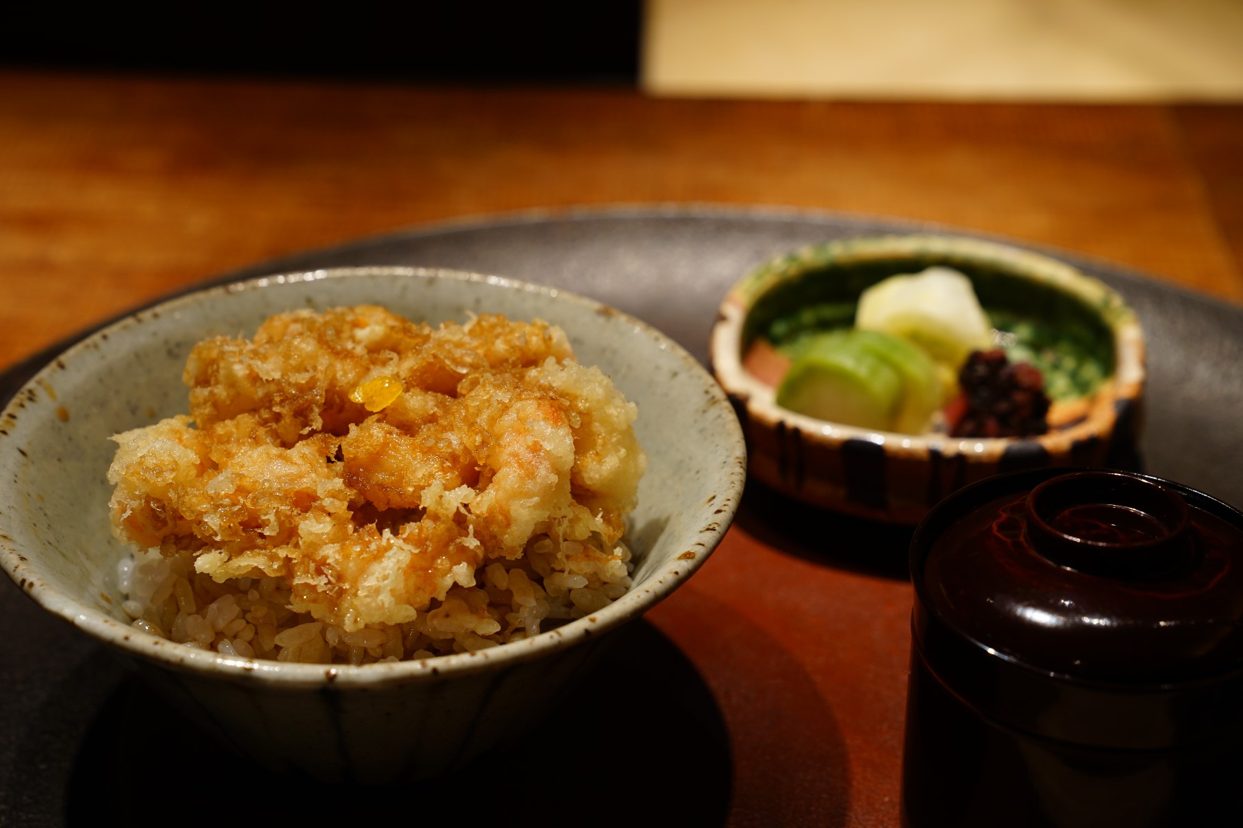 Tendon rice bowl with a kakiage fritter, pickles and a lacquered soup bowl in Motoyoshi’s official menu photograph.