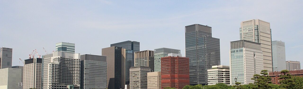 An archival view of Marunouchi and Otemachi towers from the Imperial Palace plaza, cropped to the skyline and trees.