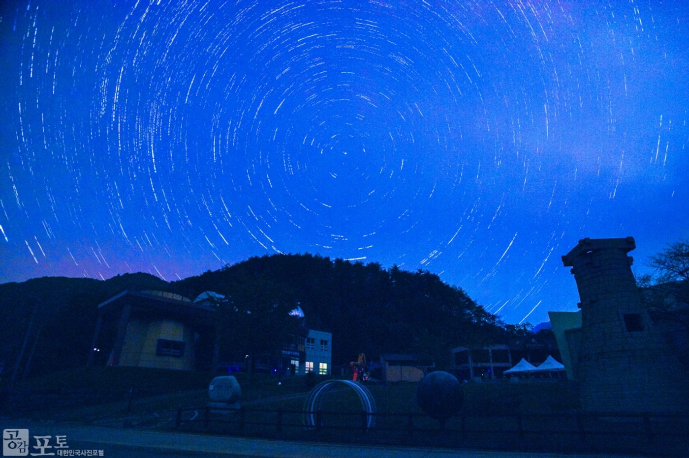 Star-trail photograph over Yeongyang observatory and astronomy models, made by accumulating light over time.