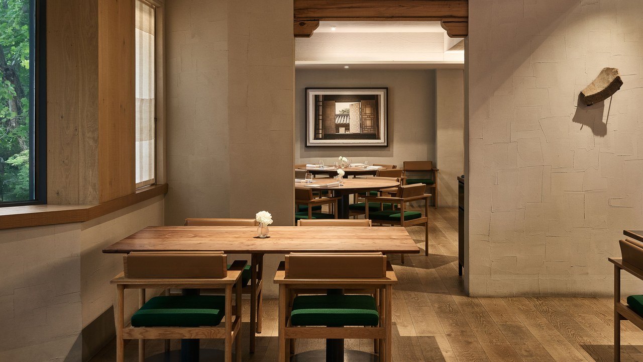 Mingles dining room with wooden tables, green-upholstered chairs and contemporary artworks.