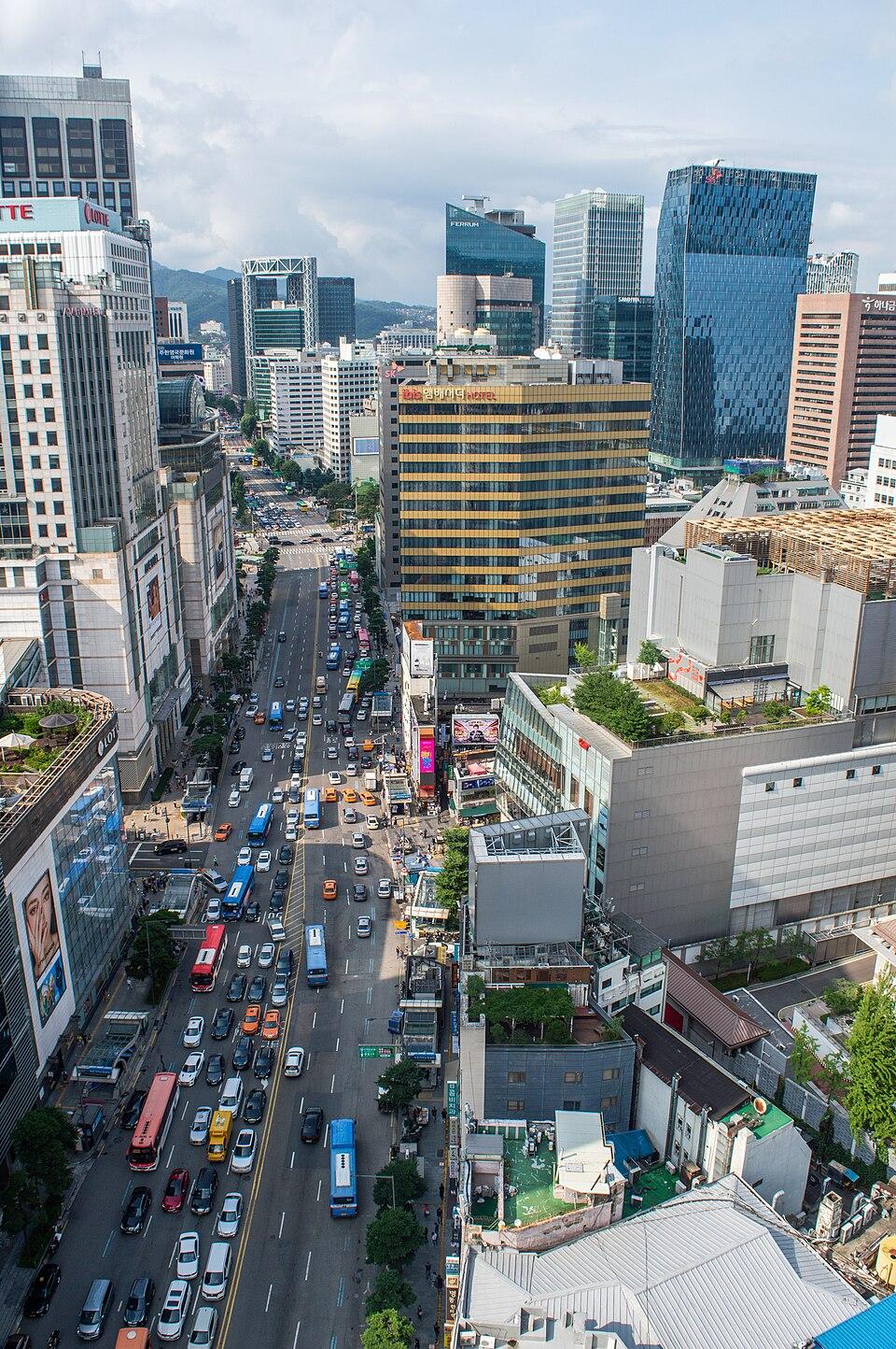 A view along Namdaemun-ro with department-store buildings and traffic, photographed from a hotel in August 2019.