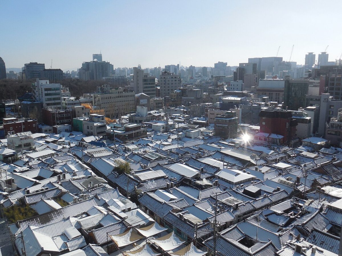 Snow-covered hanok roofs in Ikseon-dong below taller Seoul buildings, January 2021.