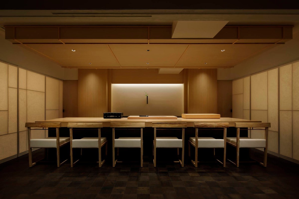 A six-seat counter room at Hakkoku, with pale upholstered chairs facing the preparation surface.
