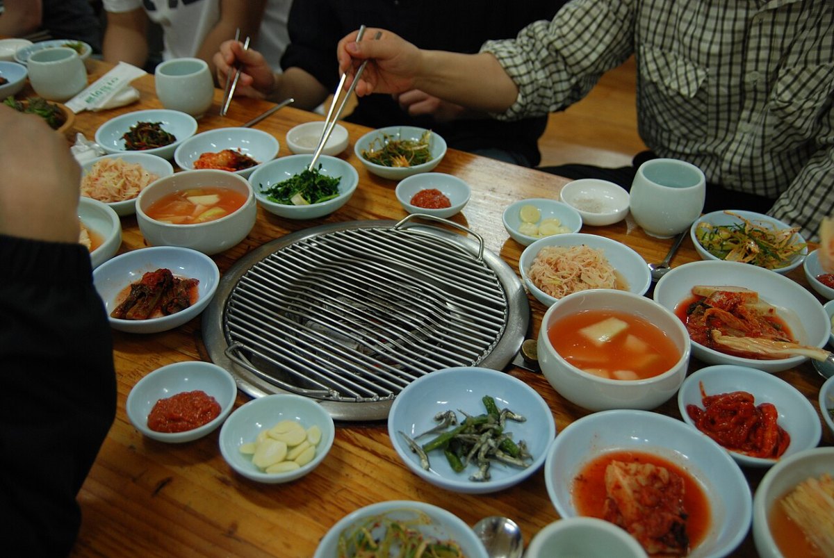Small dishes of vegetables and other banchan arranged around a Korean barbecue grill in Hoenggye.