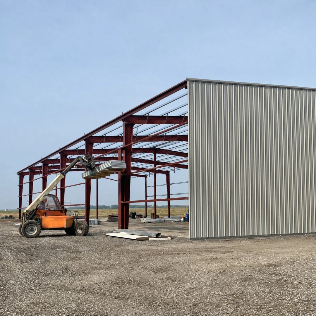 Pre-engineered metal building going up with steel frames, purlins and the first wall panels in place