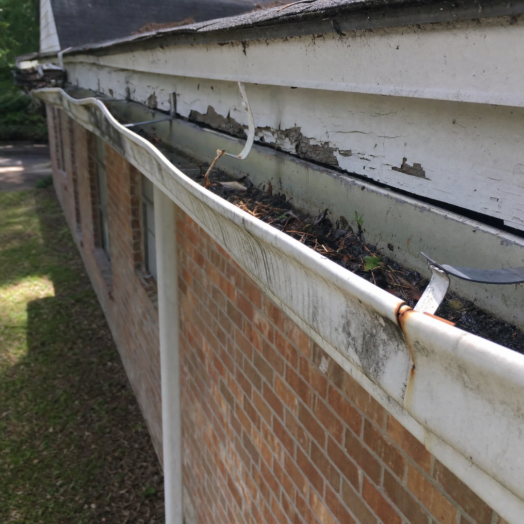 Sagging, separated old gutter pulling away from the fascia board before replacement