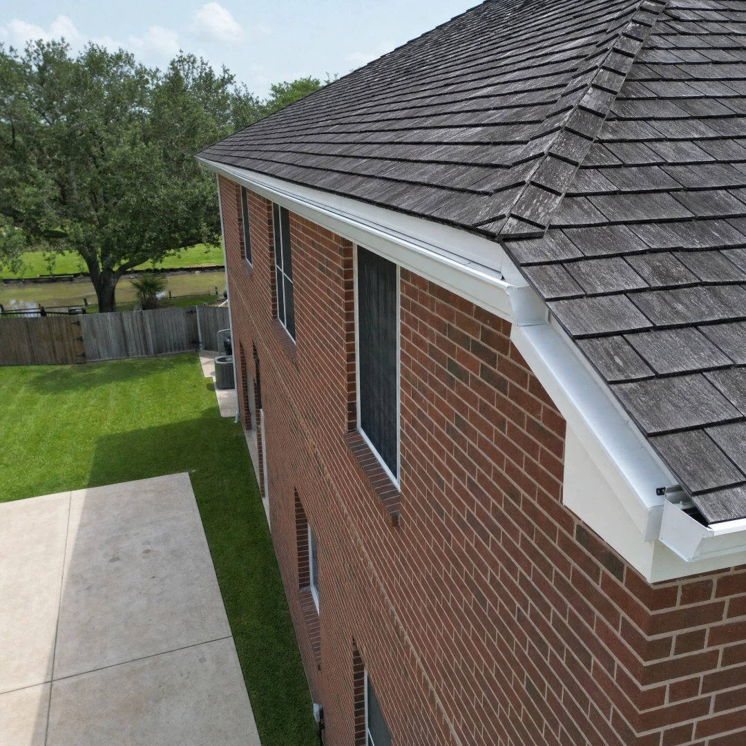 Aerial view of new seamless gutter running the full length of a hip roof on a brick home