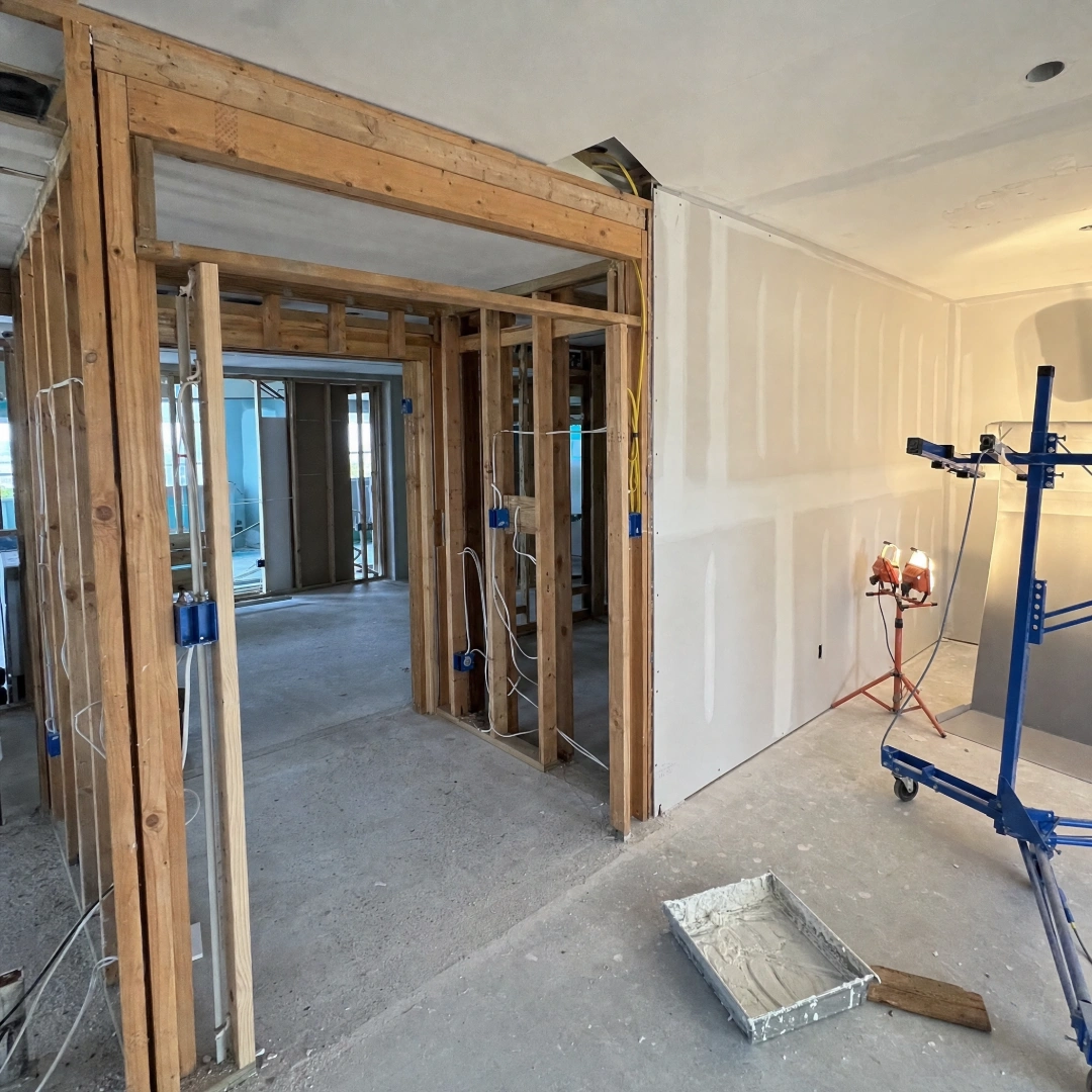 Interior remodel in progress showing new stud framing, electrical rough-in and freshly hung drywall with taped seams