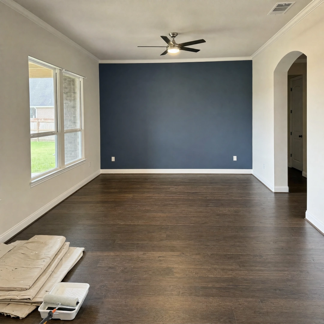 Painter rolling a fresh coat of neutral paint across an interior wall during a whole-room repaint