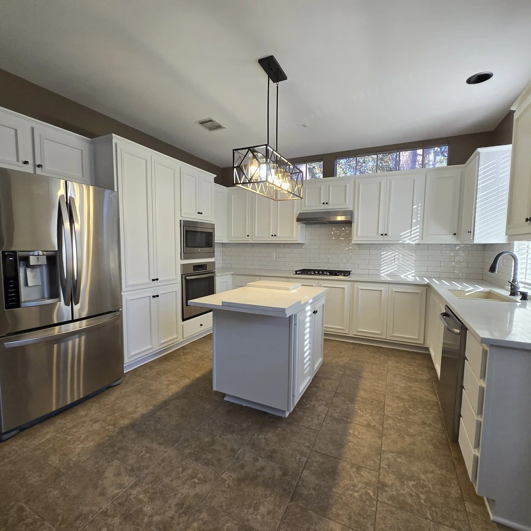 Remodeled kitchen with white shaker cabinets, a center island, stainless steel appliances and pendant lighting