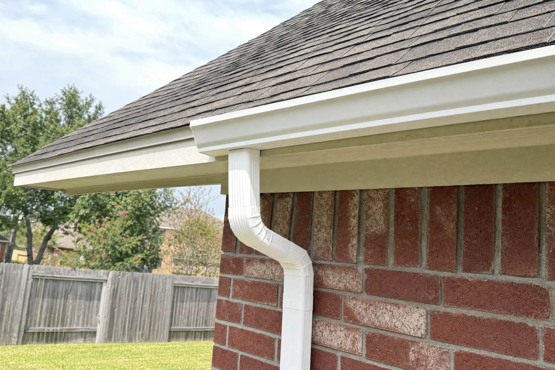 New white aluminum seamless gutter and downspout on a brick home in Cypress, Texas