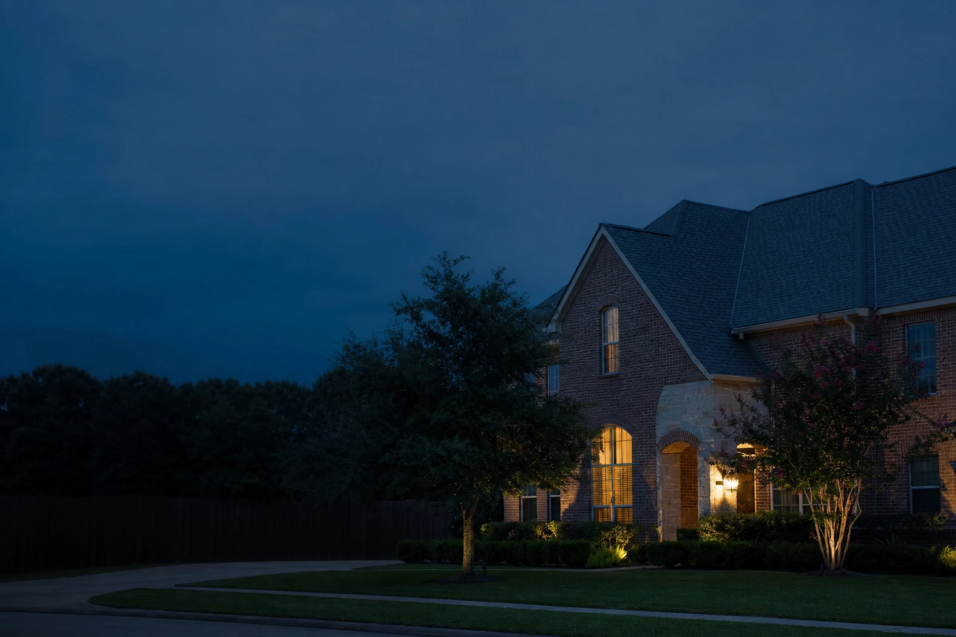 Two storey brick home with a new architectural shingle roof at dusk in Cypress, Texas