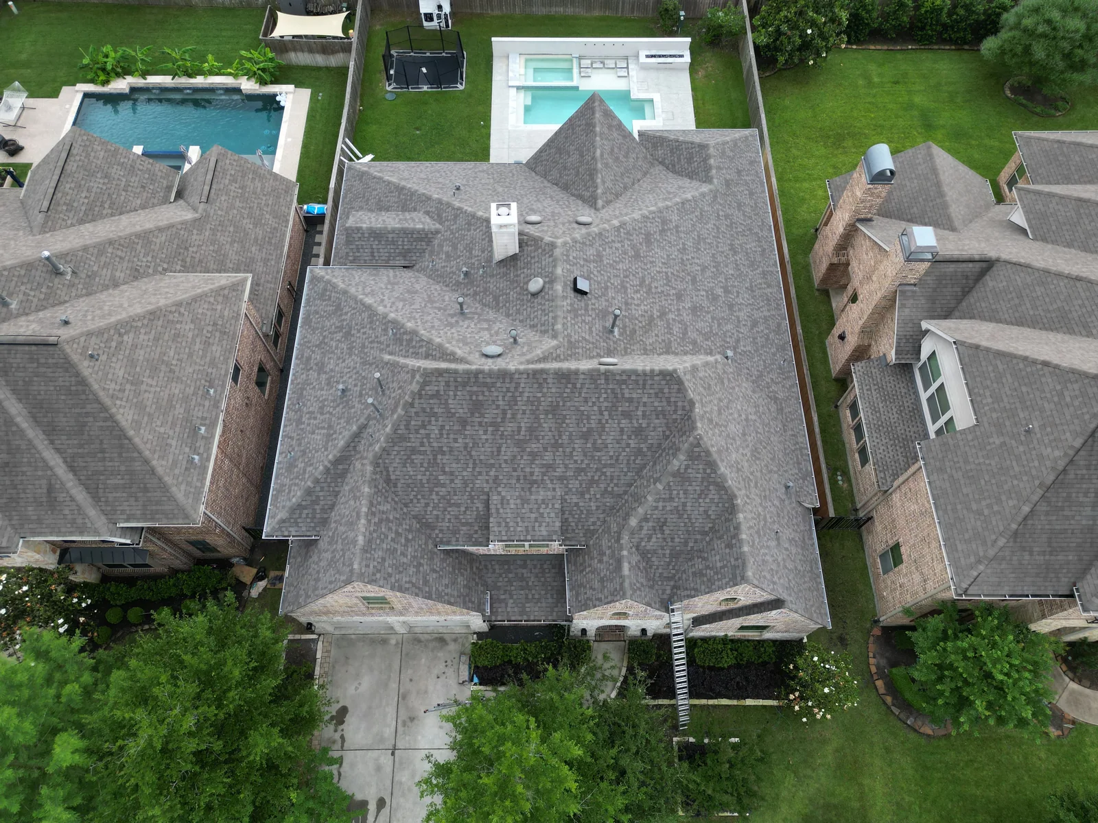 Aerial view of a new grey shingle roof on a Houston two story home with a backyard pool