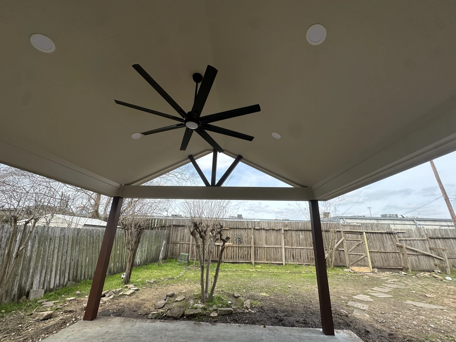 Covered patio with a white painted ceiling and stained posts over a new concrete slab in Houston