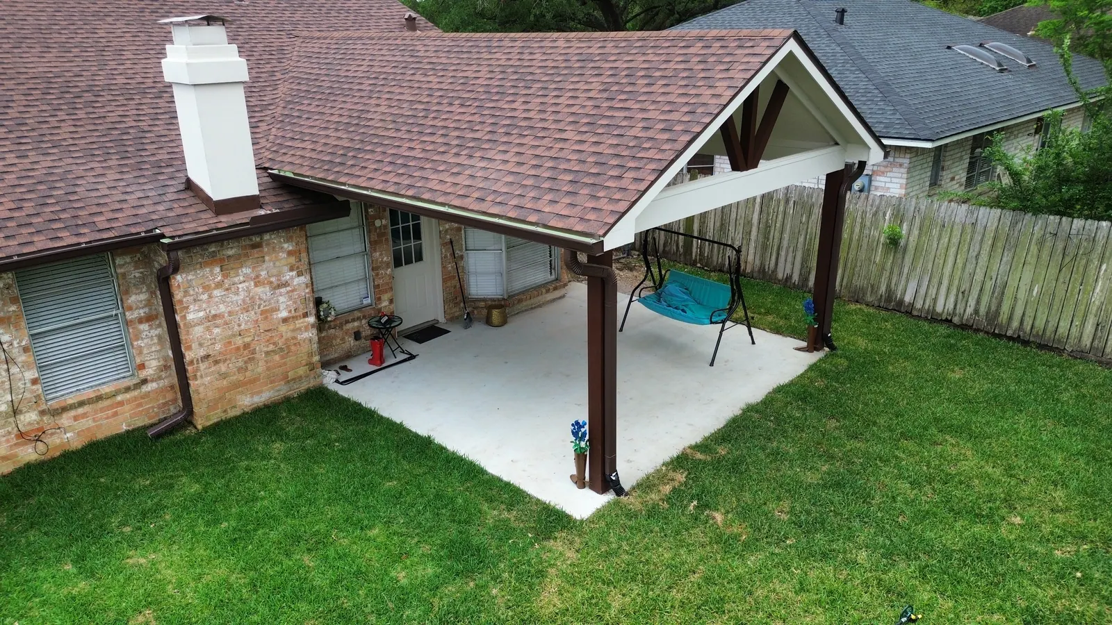 Covered patio addition with a gable roof and stained wood posts on a Houston brick home