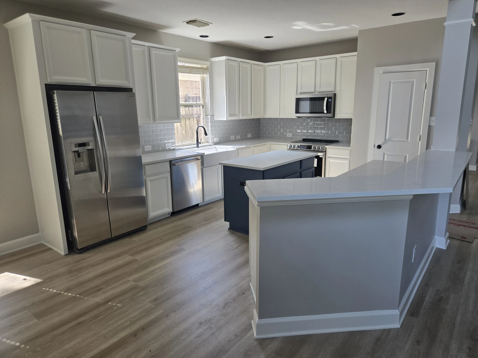 Remodeled kitchen with white shaker cabinets, a grey island and quartz countertops in Houston TX