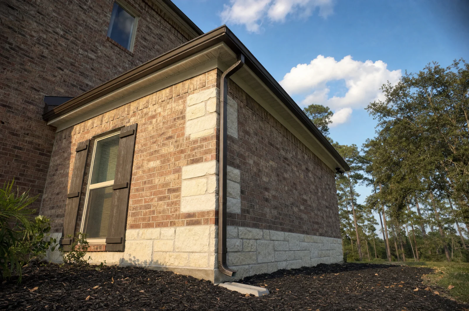 Finished bronze seamless gutter and downspout on a brick and stone Houston area home