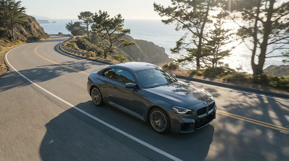 Grauer BMW M2 auf einer Küstenstraße im Gegenlicht