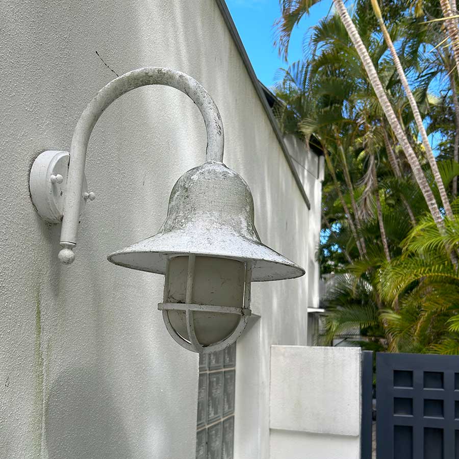 Grimy exterior house lamp and wall before pressure cleaning