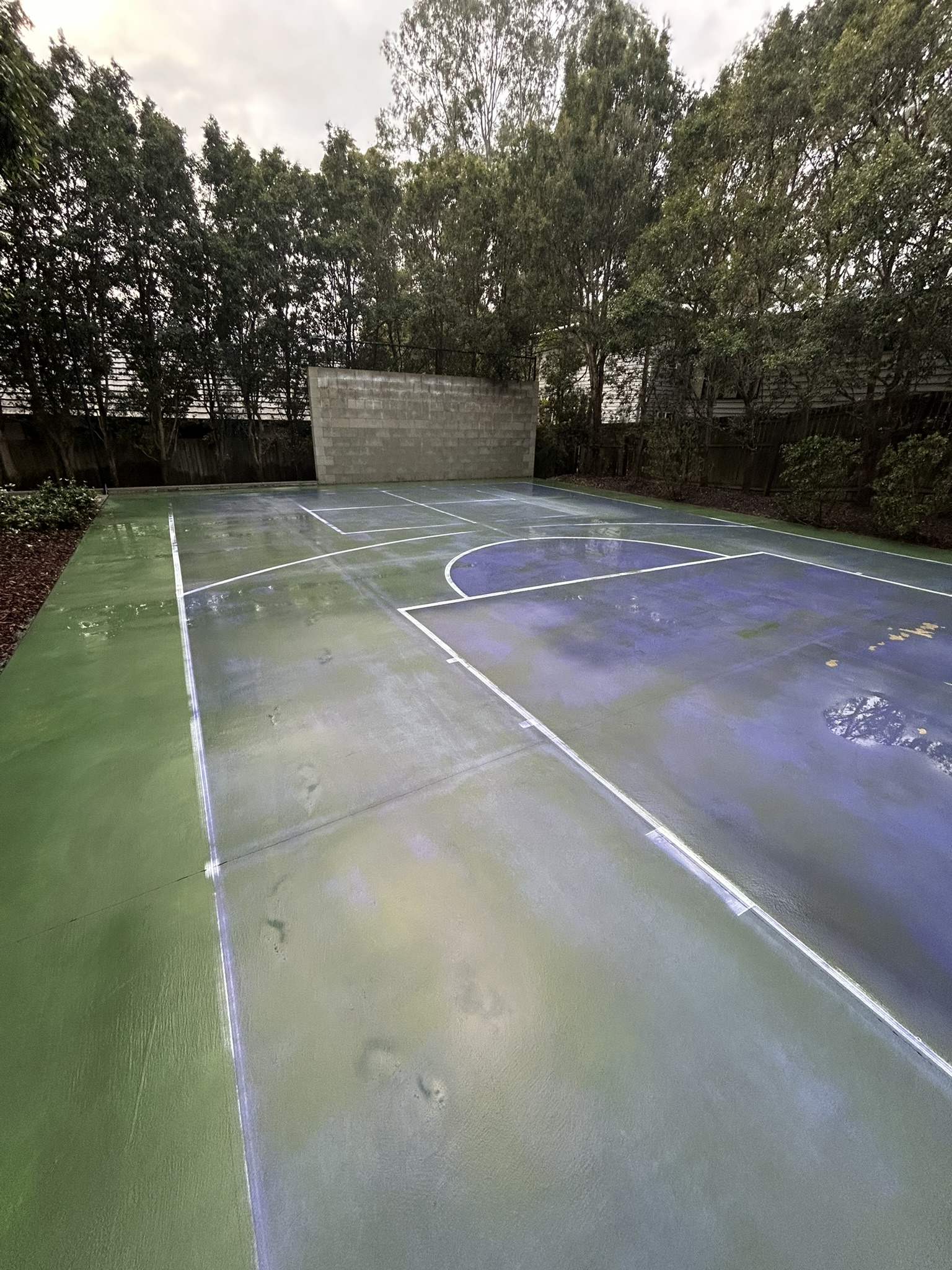A tennis court surface after cleaning, with the line markings visible again