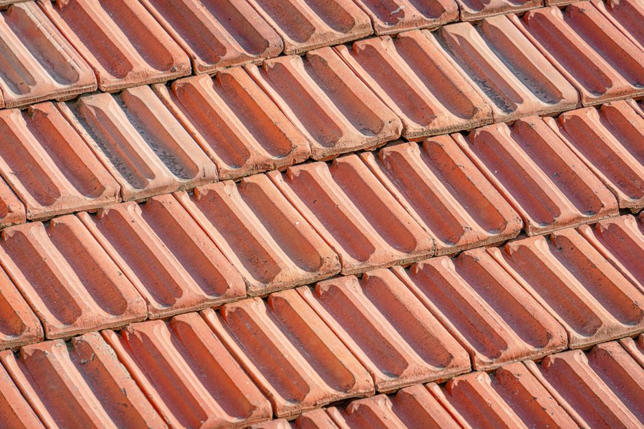 Detailed view of overlapping terracotta tiles forming a textured rooftop surface.