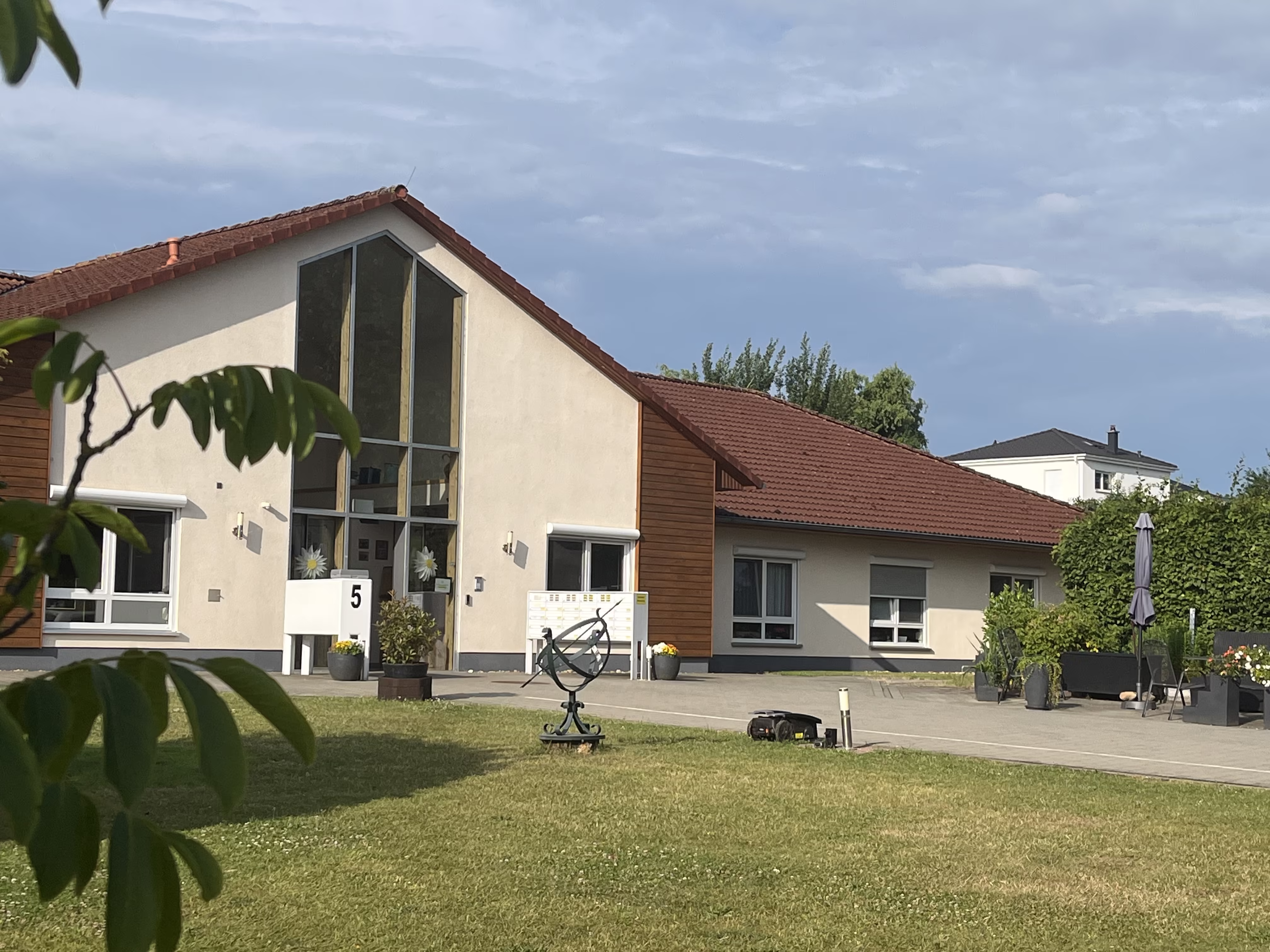 Weitwinkelansicht des Seniorenzentrums an der M&uuml;hle mit Rasenfl&auml;che, Sonnenuhr und &uuml;berdachter Terrasse