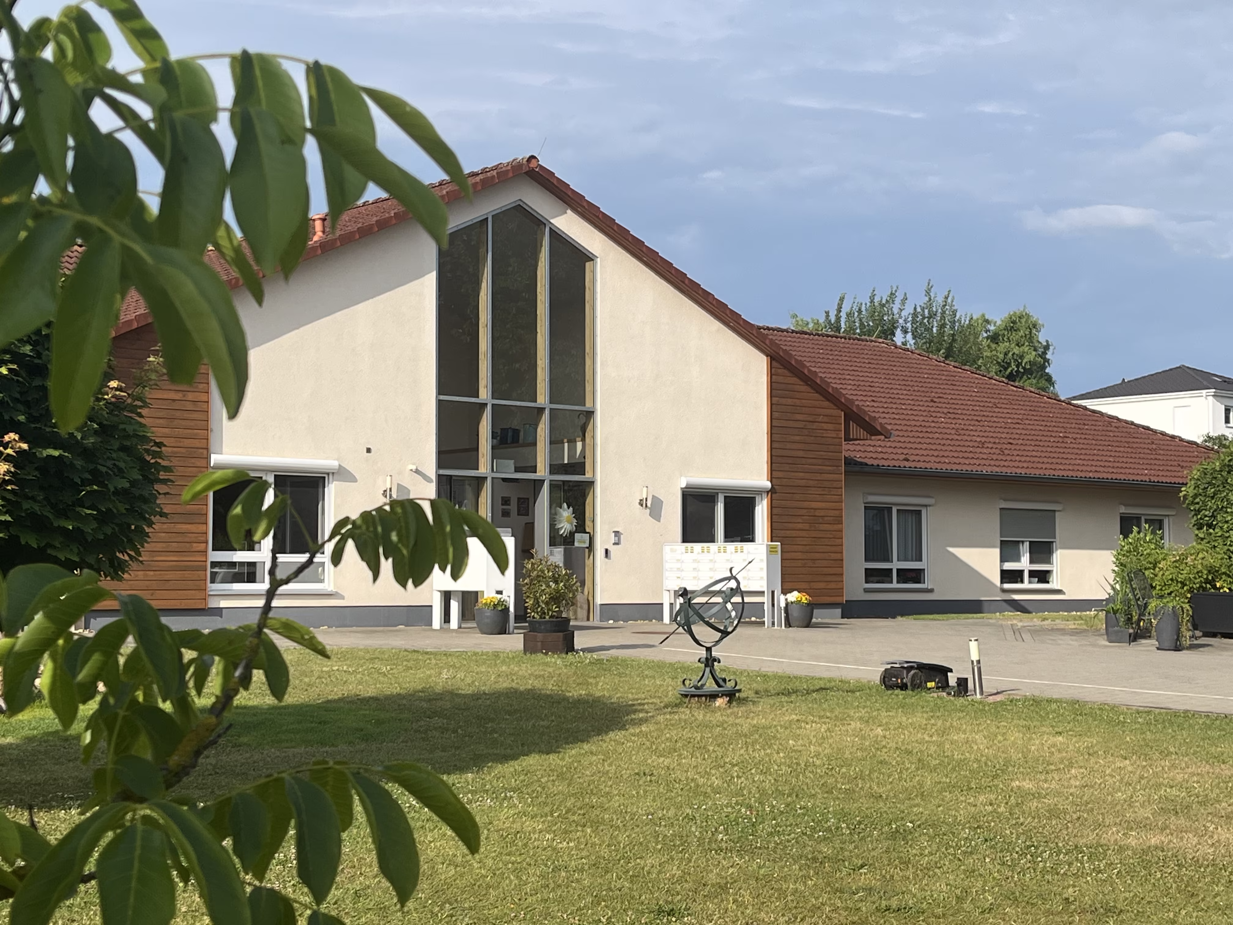 Blick durch das Laub eines Baumes auf den Glasgiebel des Seniorenzentrums an der M&uuml;hle