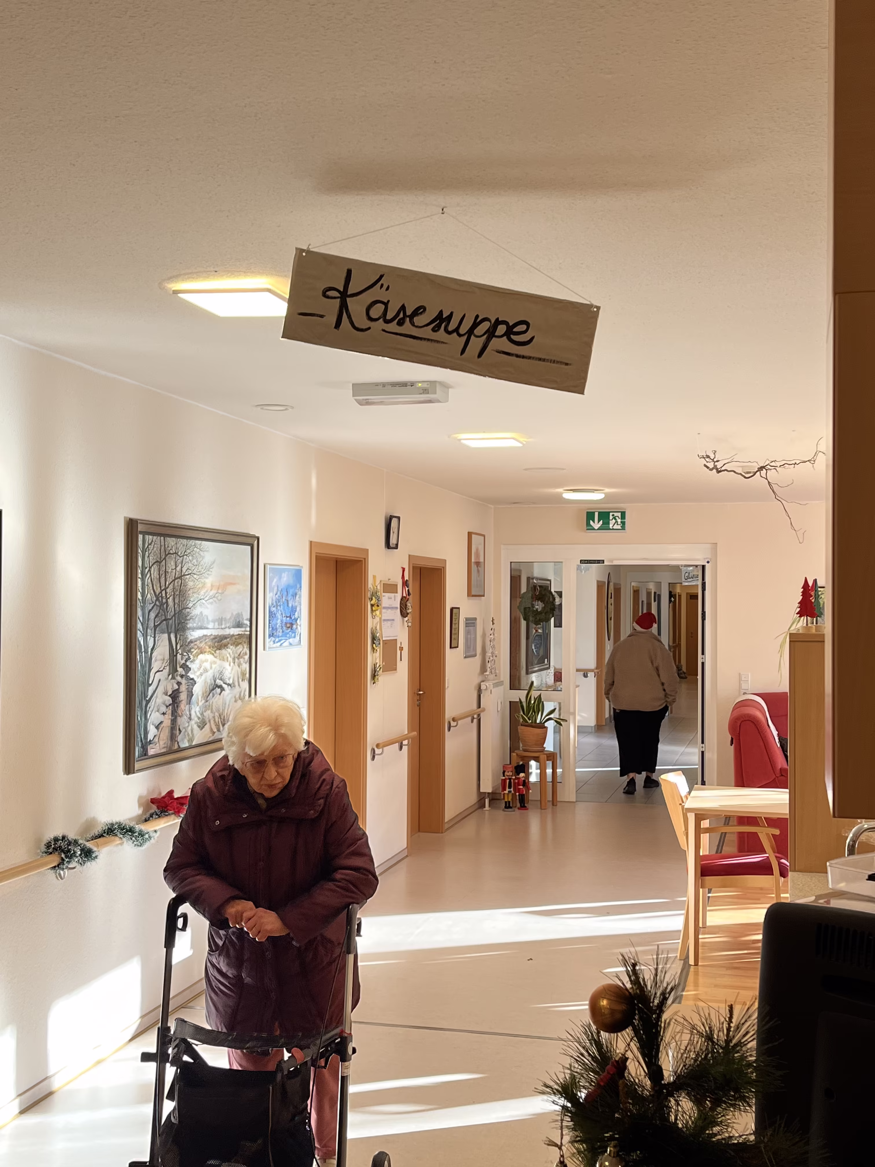 Bewohnerin mit Rollator im hellen Flur des Seniorenzentrums an der M&uuml;hle