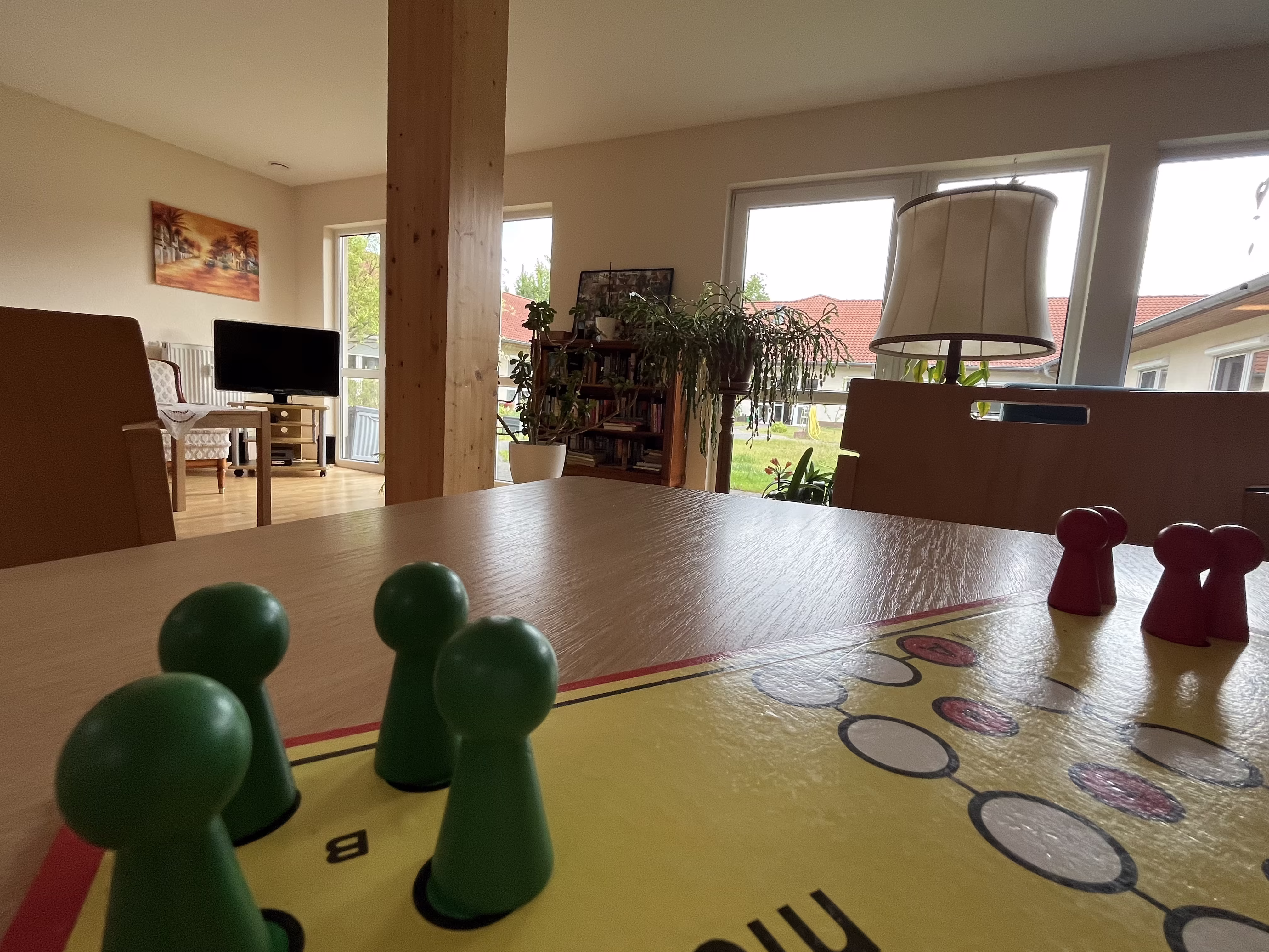 Spielnachmittag im Seniorenzentrum: Spielfiguren auf dem Brettspiel auf der hellen Gemeinschaftsfl&auml;che
