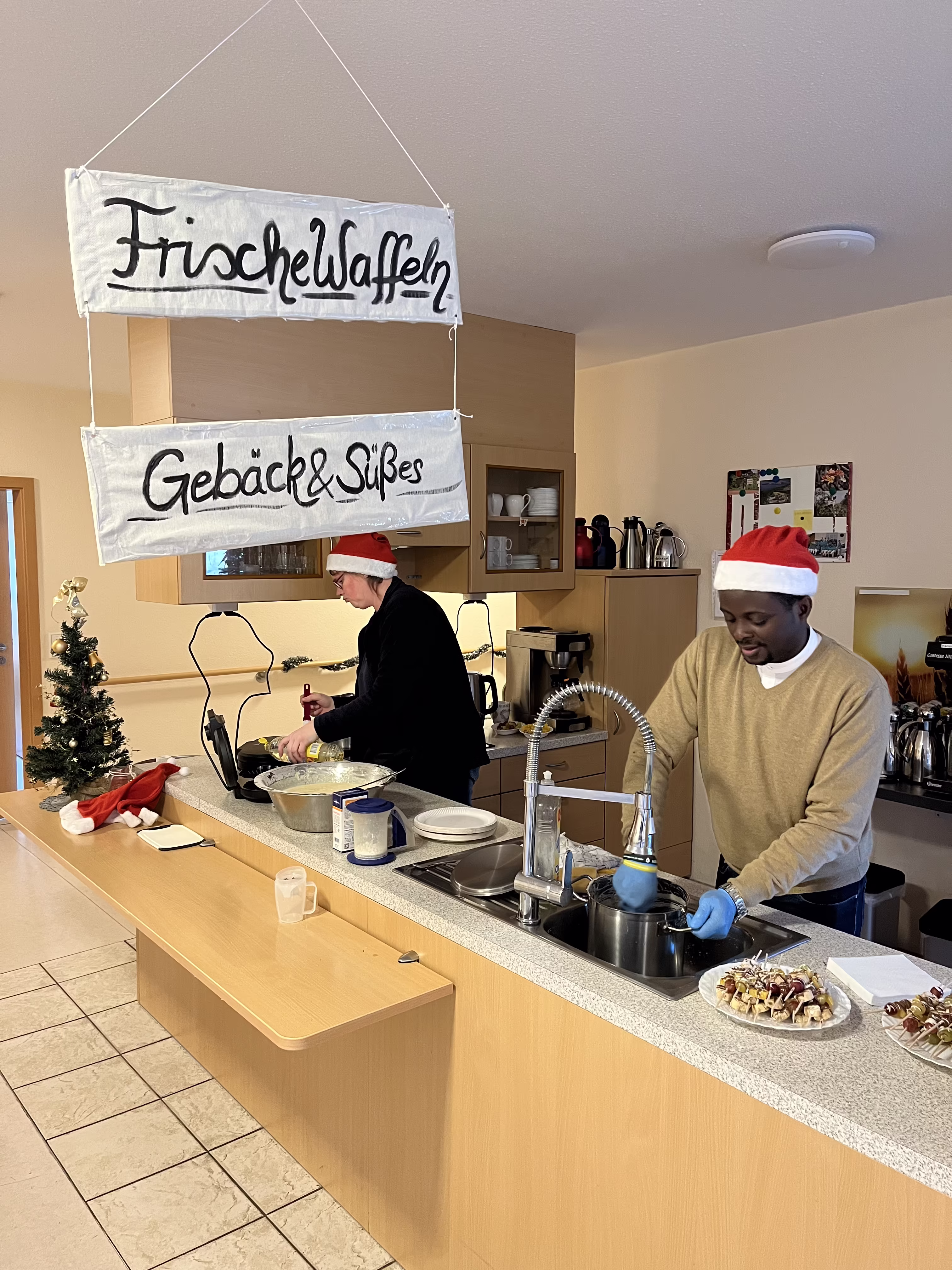 Mitarbeitende bereiten in der offenen K&uuml;che Waffeln und Geb&auml;ck f&uuml;r den Adventsnachmittag zu