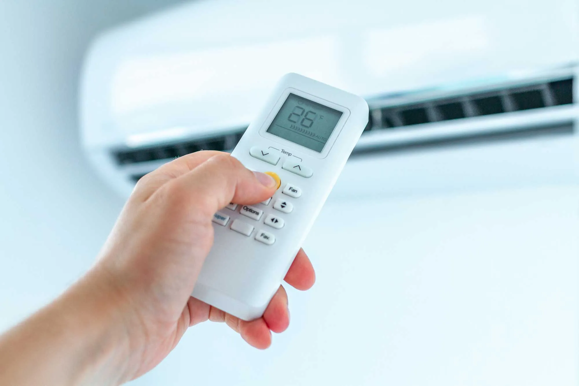 A person controlling an air conditioning unit with a remote