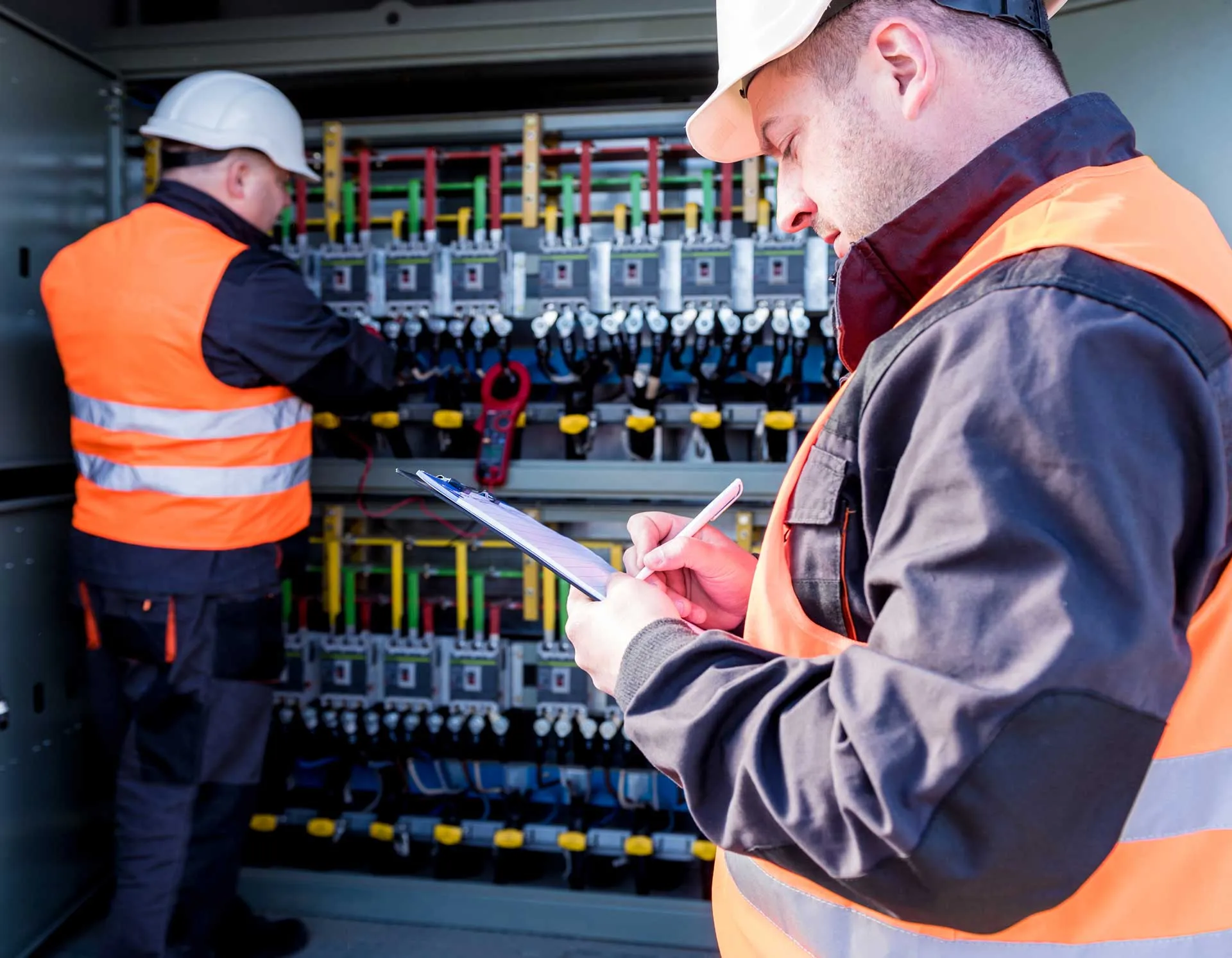 Two engineers working on a large electrical junction box