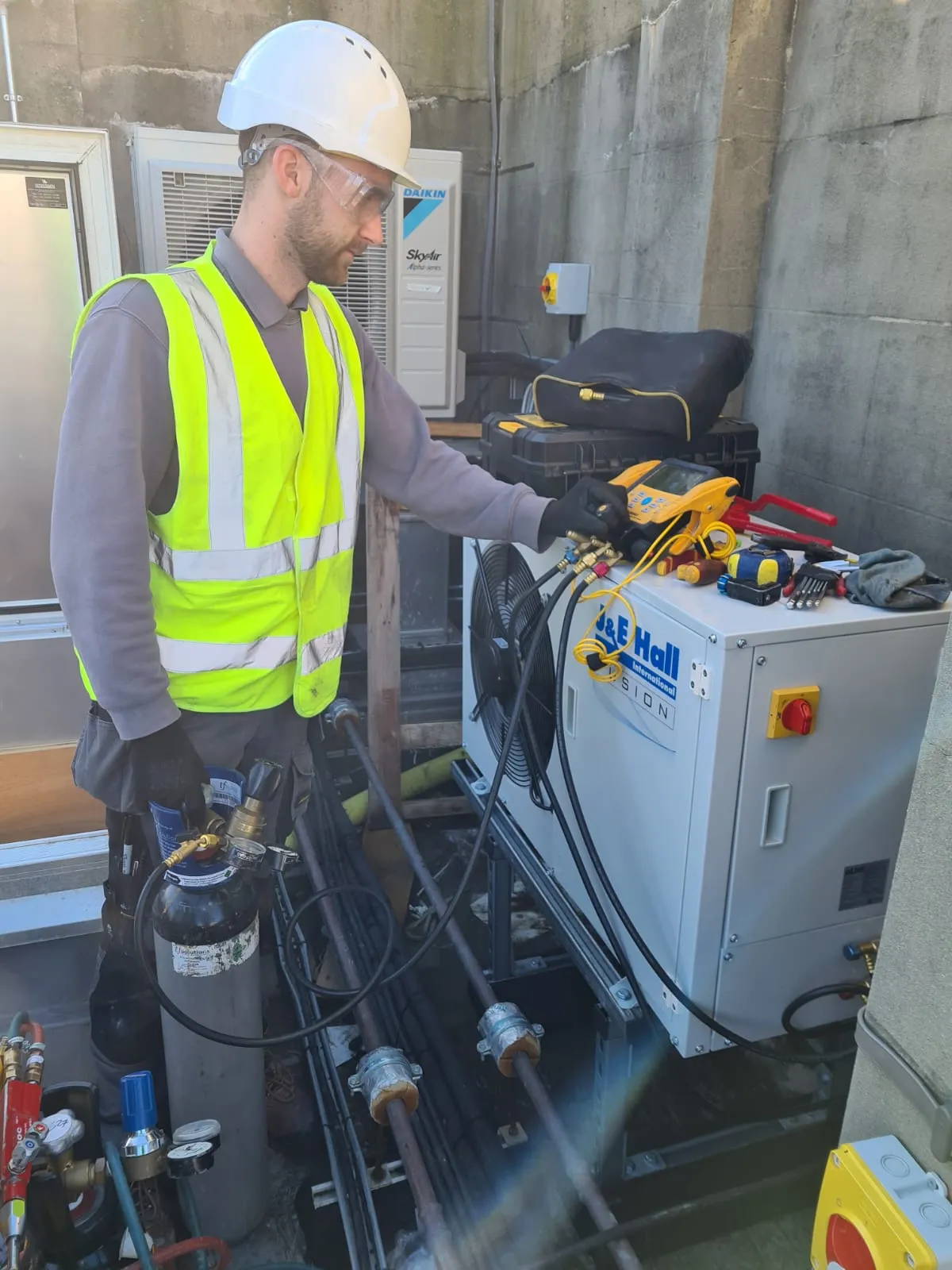 An engineer working outside on a refrigeration condenser unit