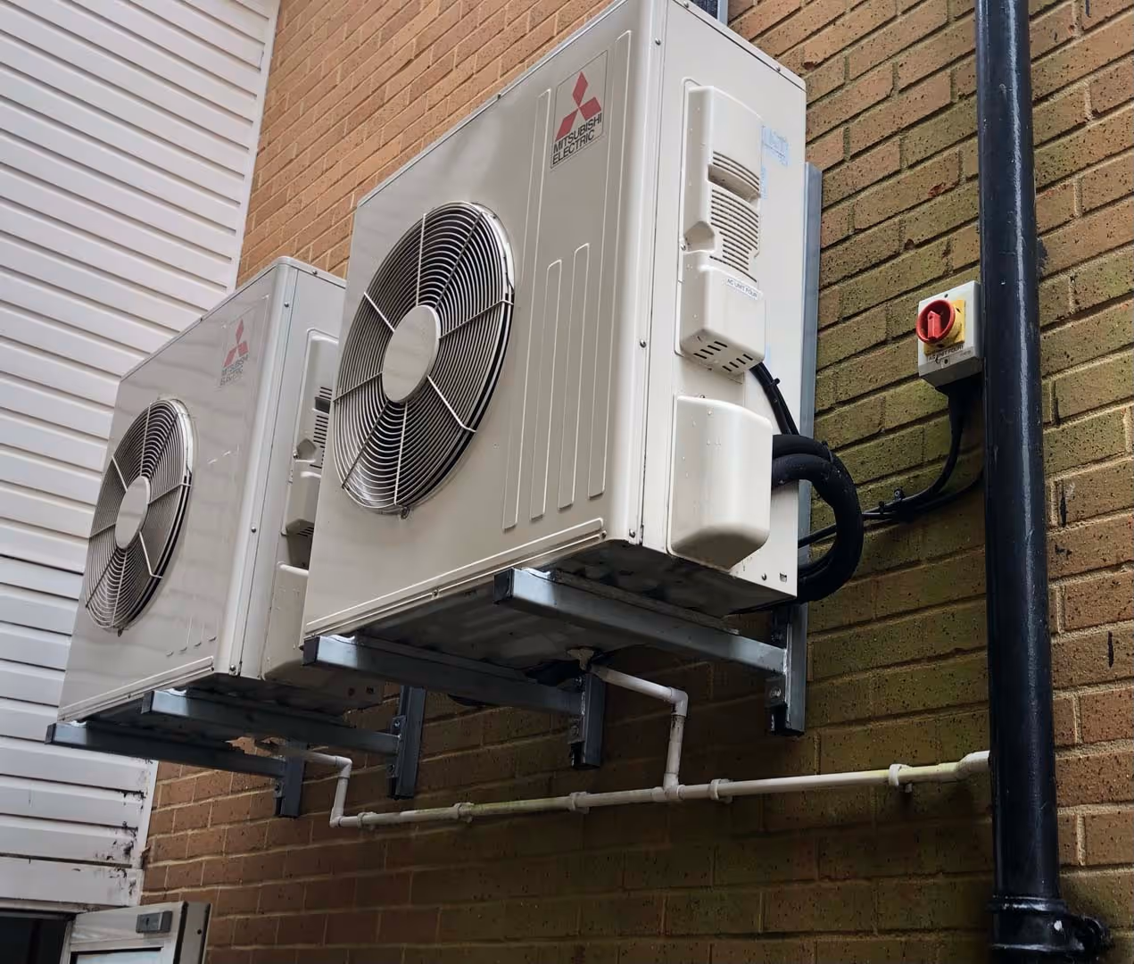 Two air conditioning units mounted on an exterior wall