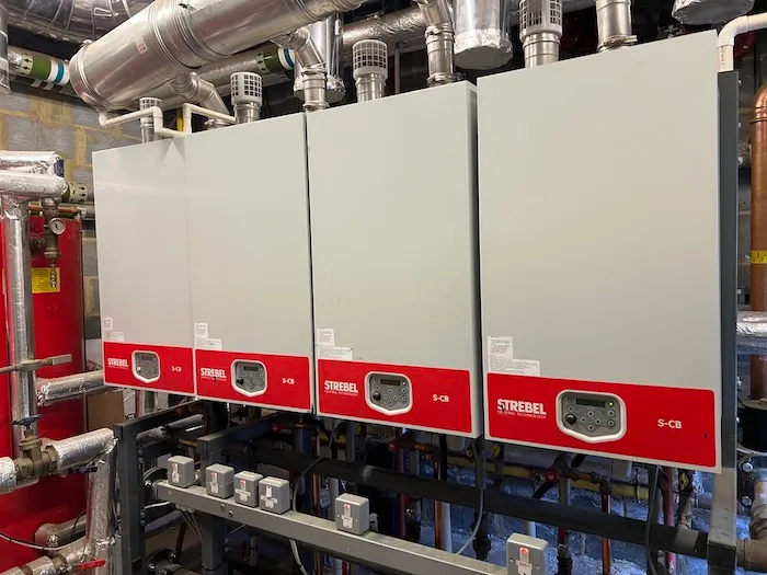 A bank of commercial boilers with connected pipework in a plant room