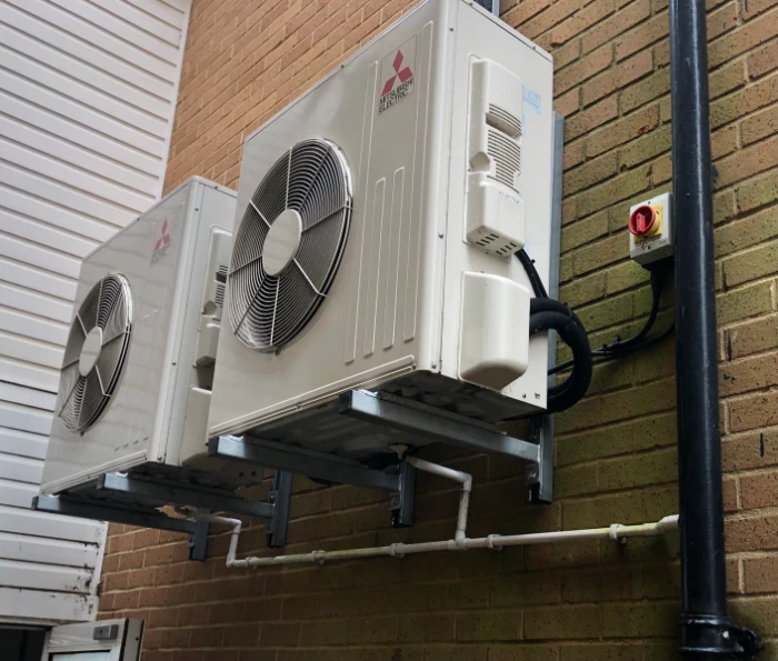 Commercial outdoor air-conditioning units mounted on brackets beside a building