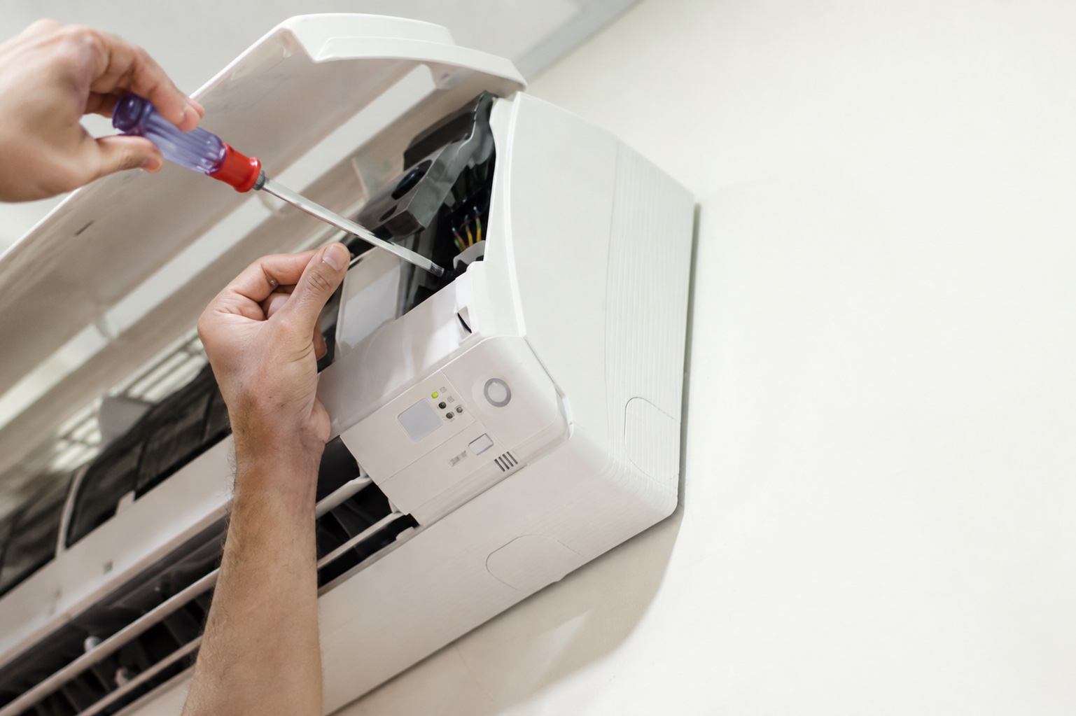 Close-up of a technician repairing the controls of an indoor air-conditioning unit