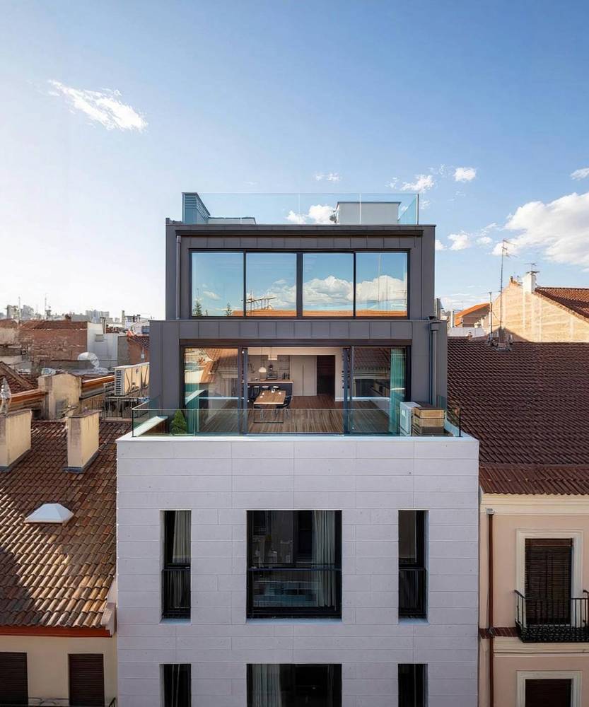 Rooftop glass penthouse above a terracotta-roofed street