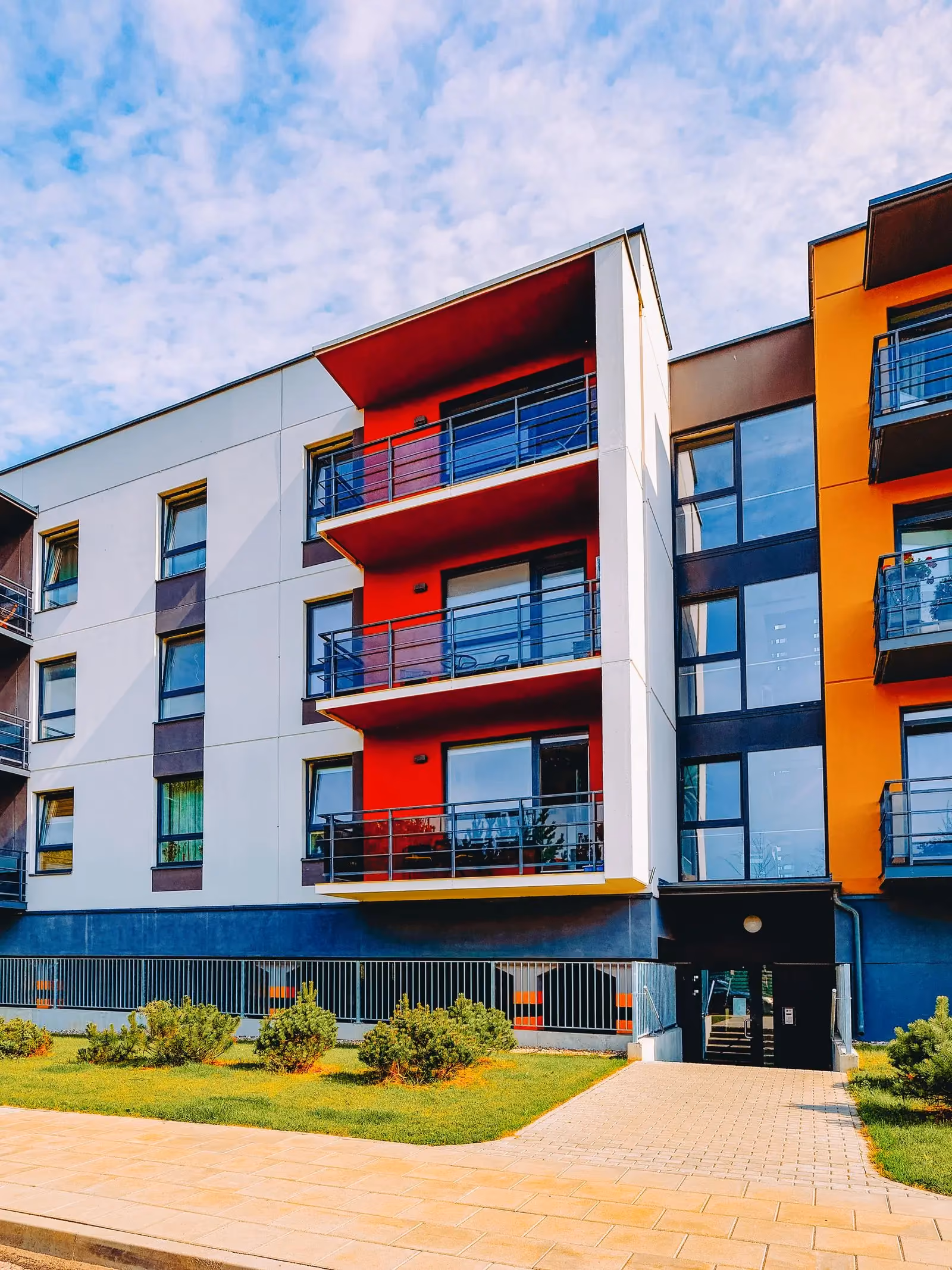 Low-rise apartment building with red and orange balconies