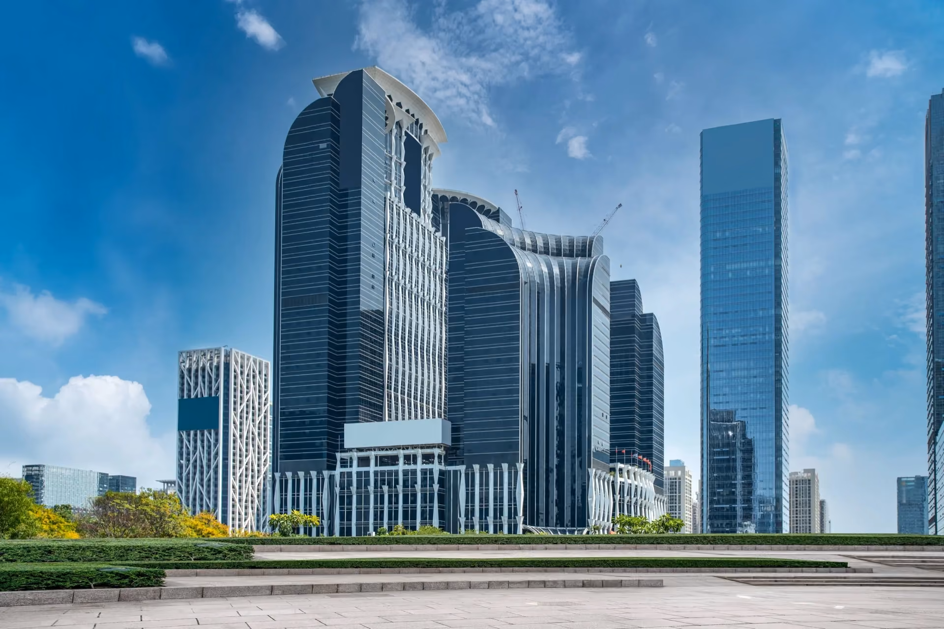 Cluster of blue glass towers behind a planted terrace