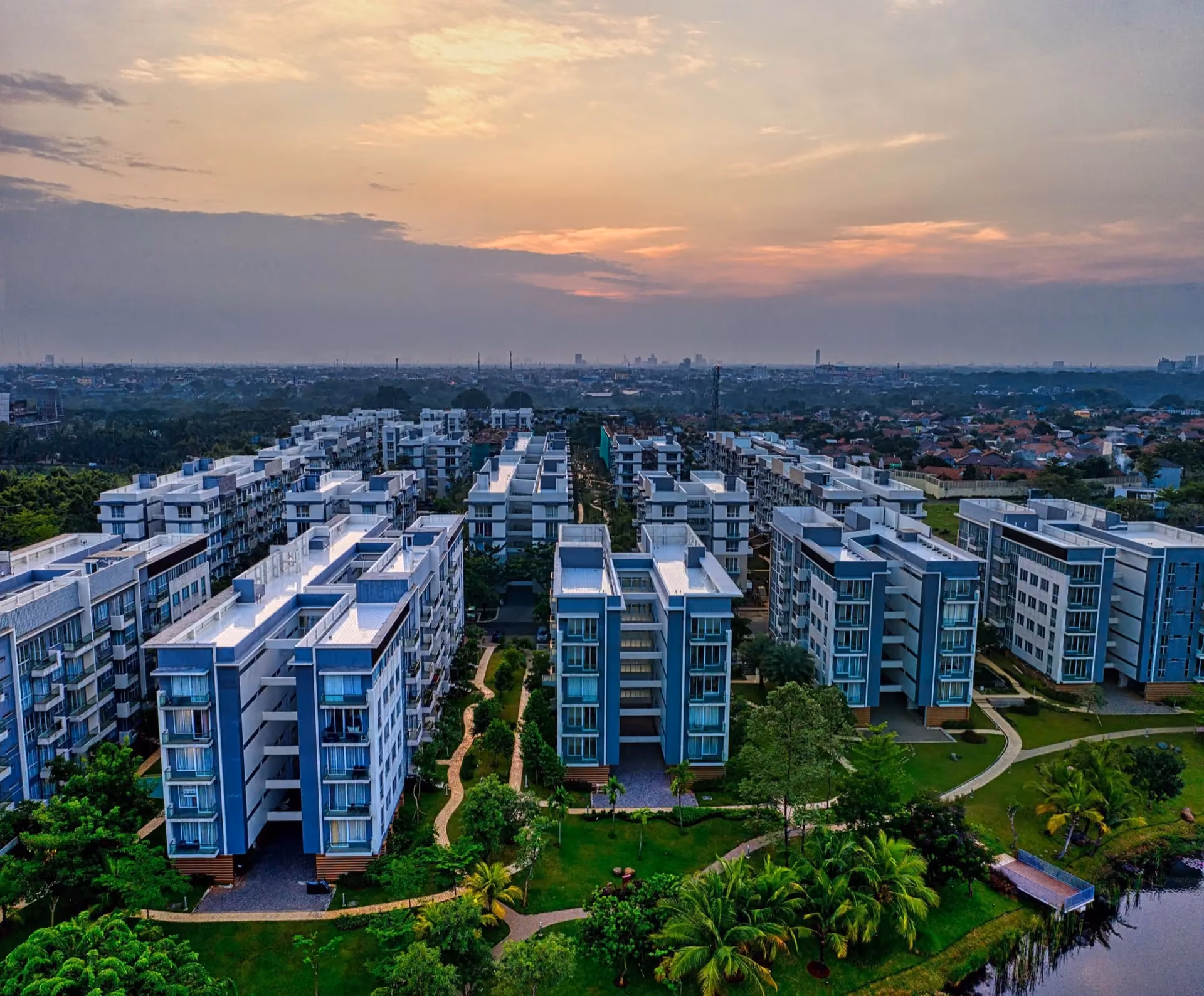 Aerial view of new apartment blocks among trees at sunset