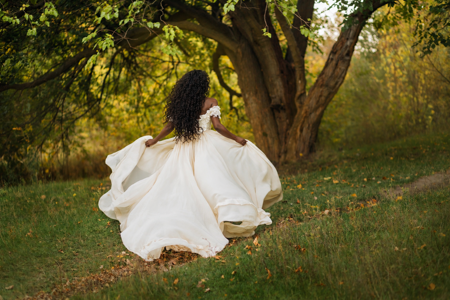 Bride in a flowing wedding gown walking through a romantic woodland setting