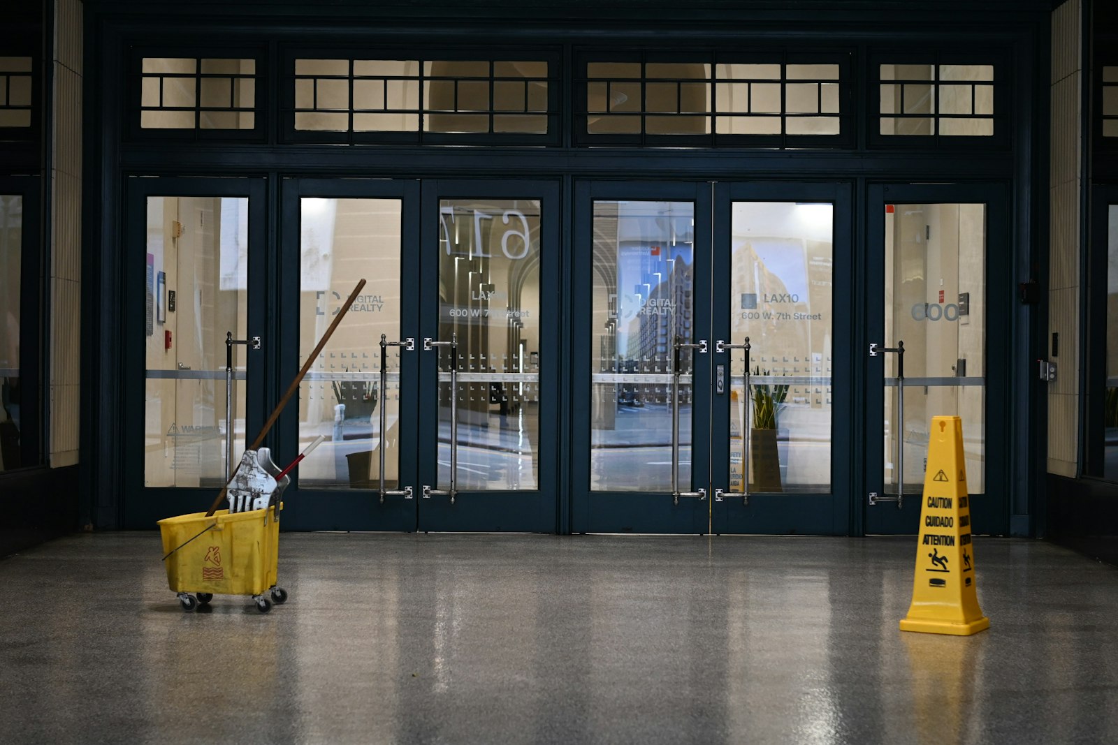 Chariot de lavage et panneau sol glissant dans le hall vitré d'un immeuble de bureaux