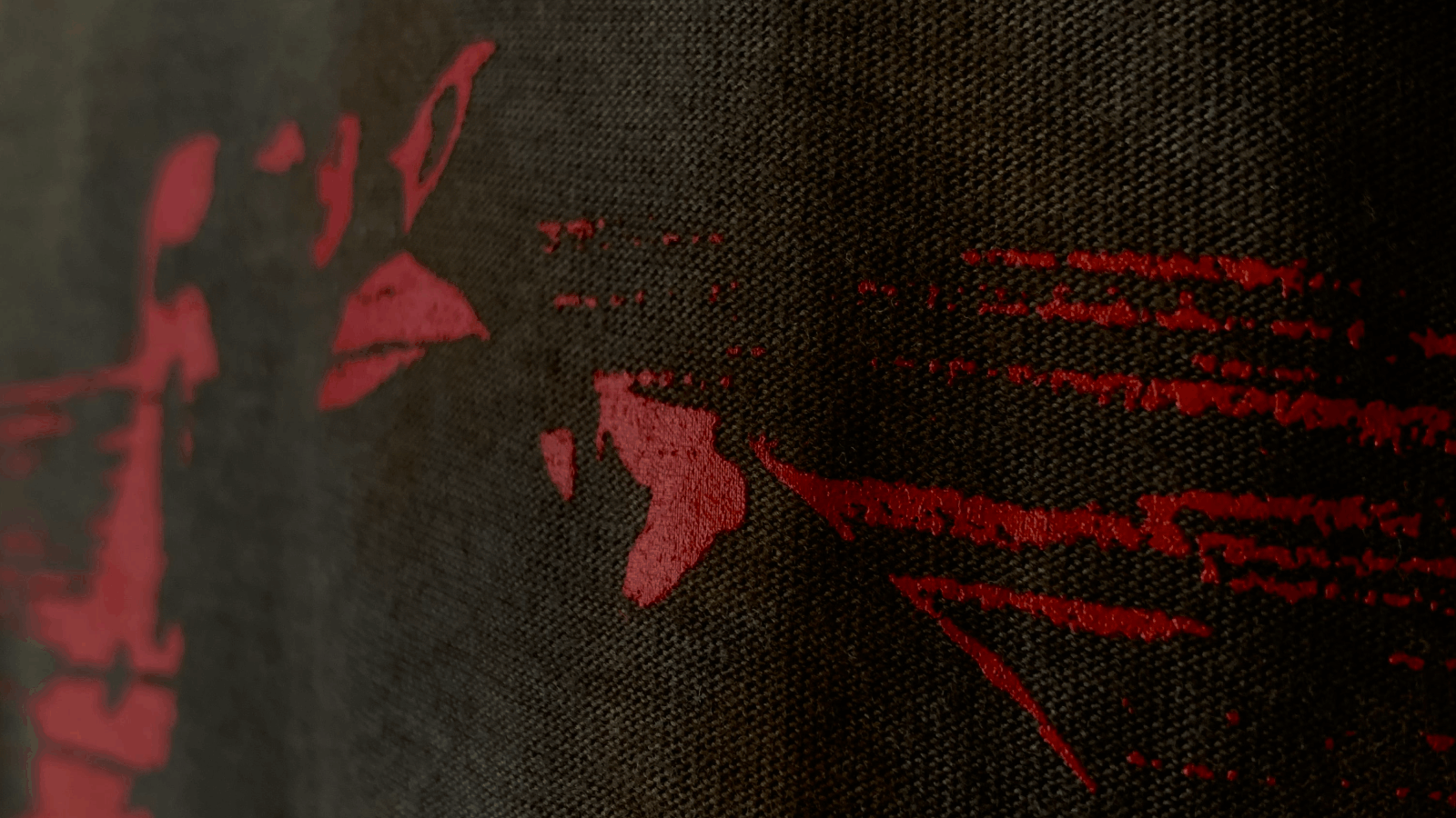 Close-up of a textured black fabric with a red abstract design printed on it.
