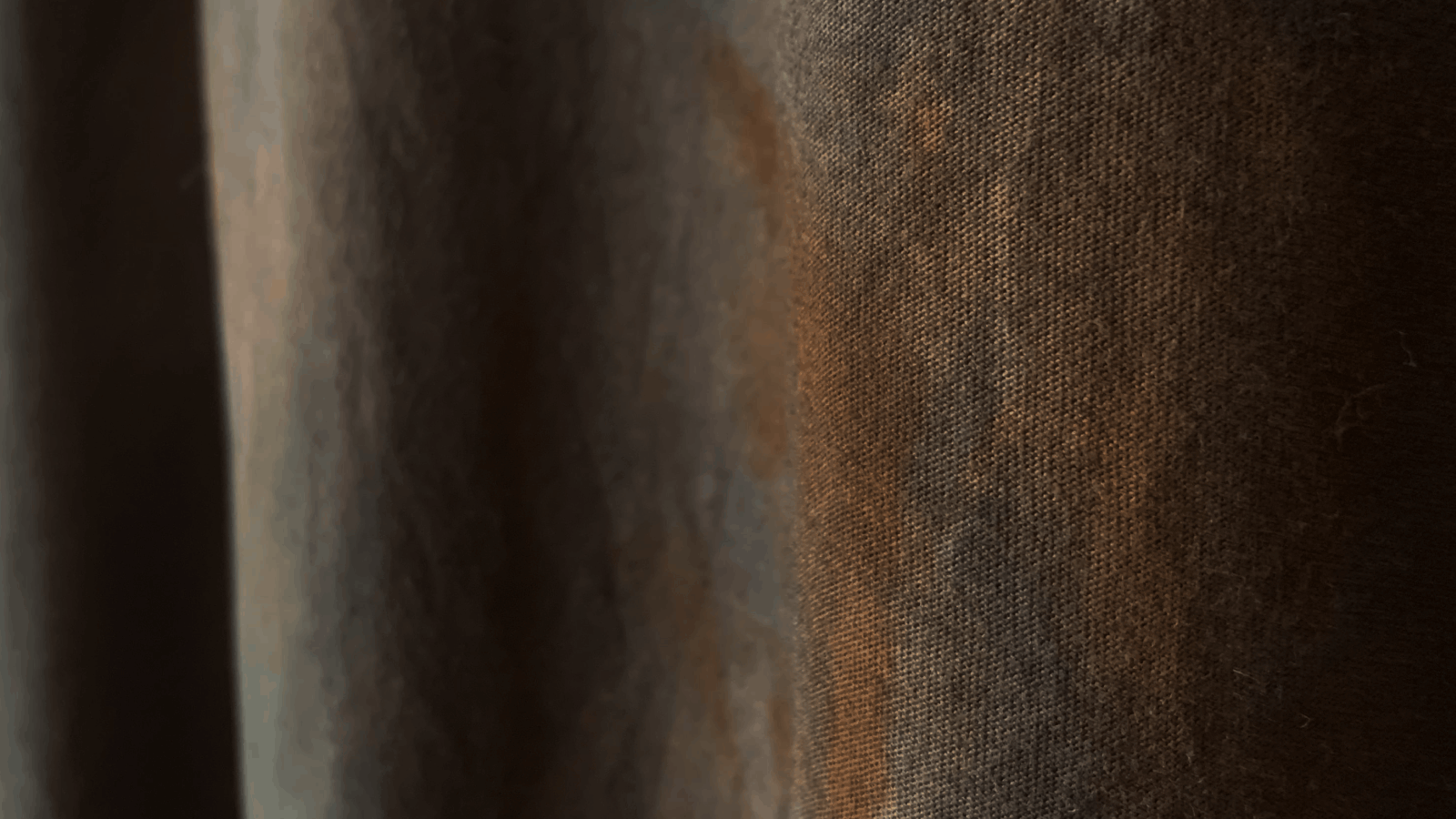 Close-up of brown fabric texture with visible weave detail and subtle shading.