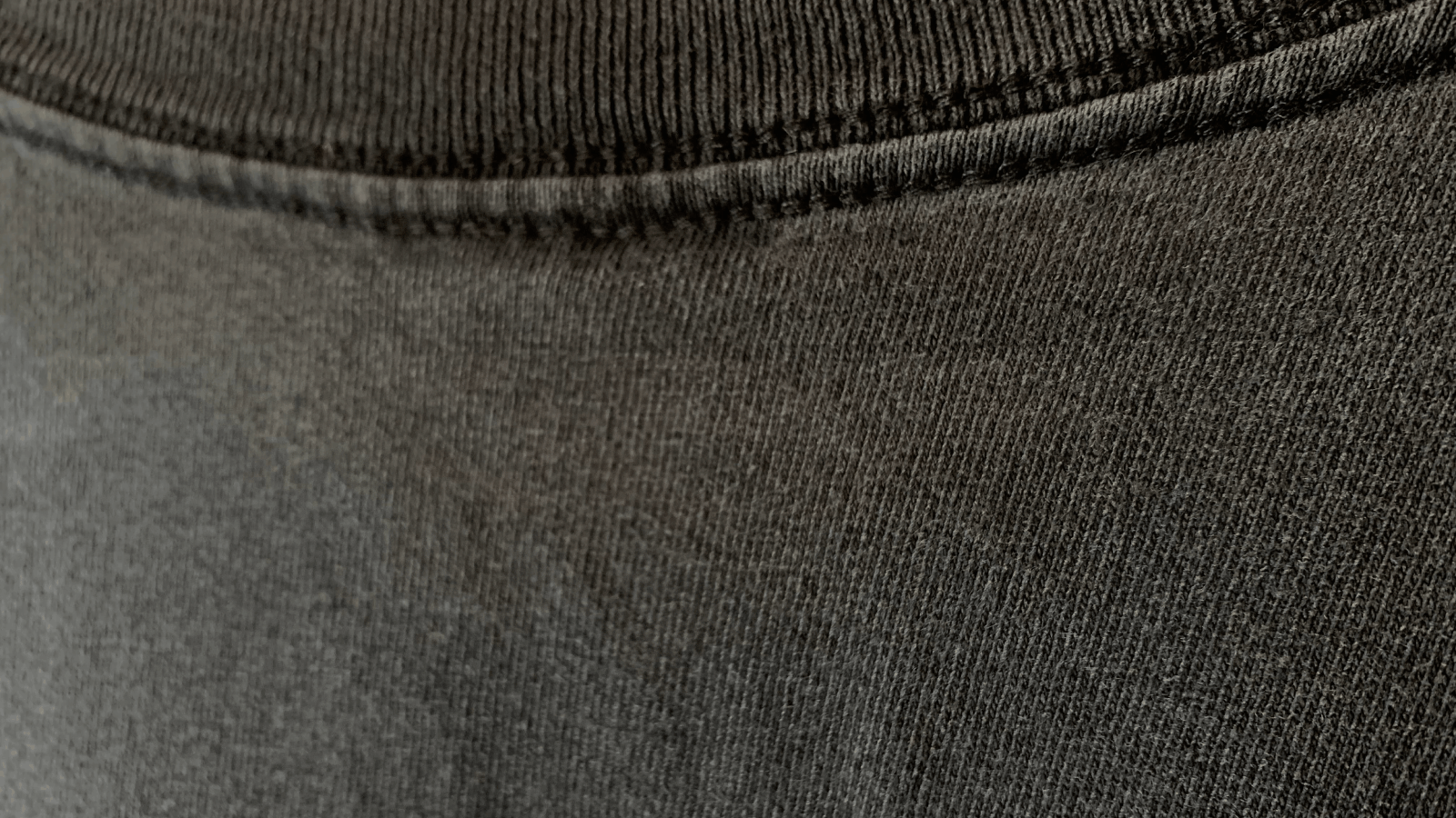 Close-up of the neckline and fabric texture of a dark gray knitted garment showing ribbed collar and stitching detail.
