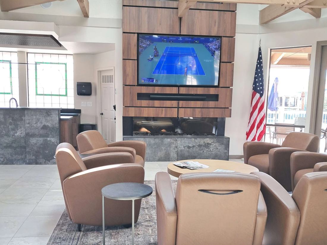 Clubhouse lounge with armchairs, a large-screen television and an open-beam ceiling.