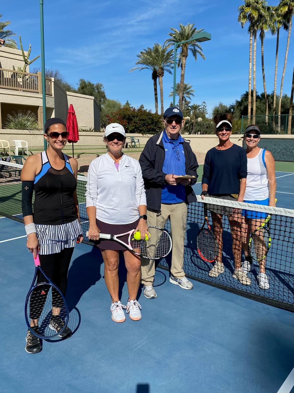Players and an event participant gathered at the net after the 2022 ladies open final.