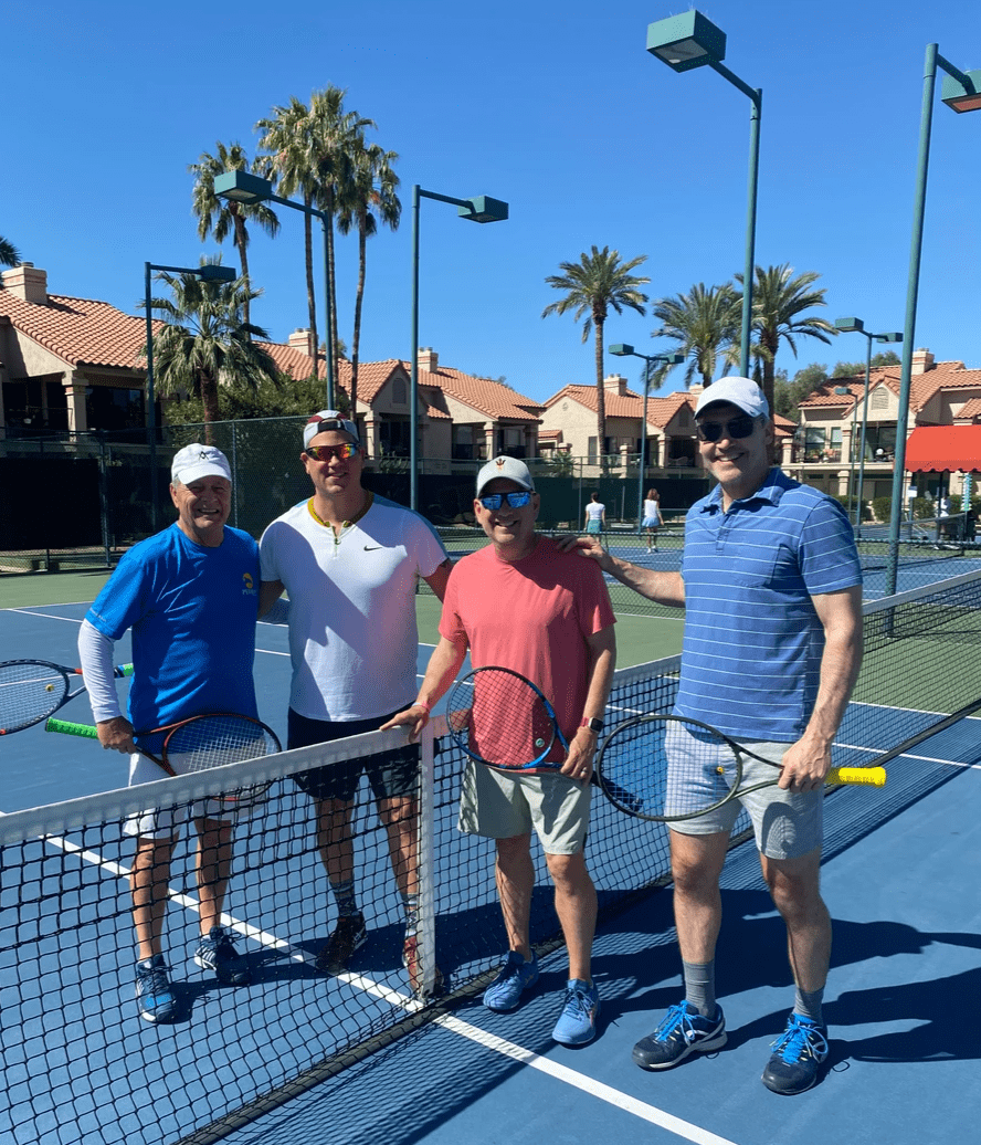 Four tournament participants with racquets lined up behind the net.
